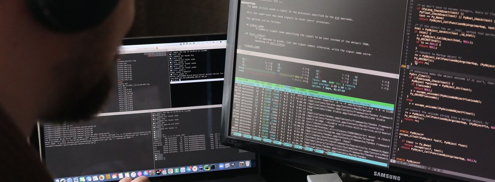 Programador revisando código en dos pantallas en un despacho en penumbra